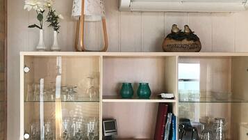 Une pièce comprenant un meuble vitrine en verre où sont exposés divers objets en verre, ainsi qu’un petit téléviseur.