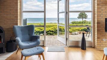A room with a large sliding glass door leading to a balcony with a view of the sea.