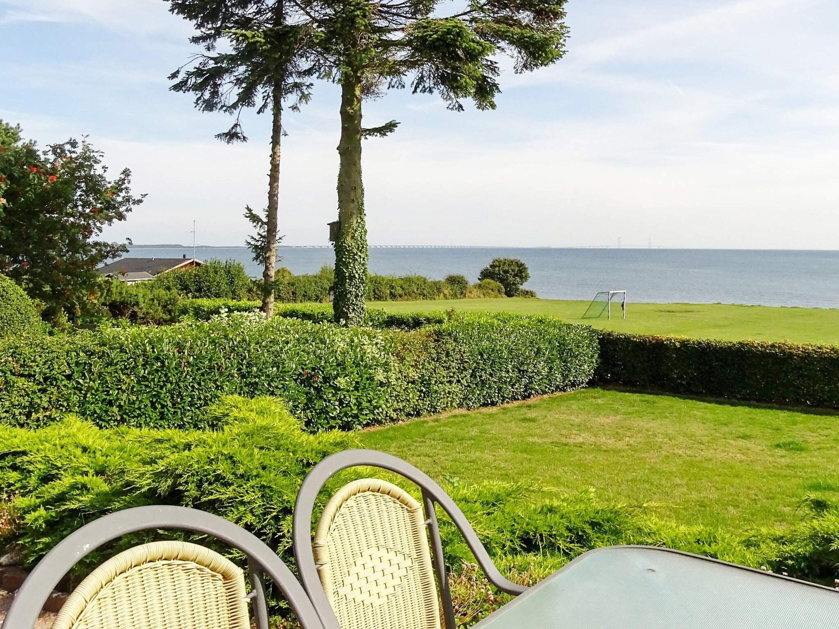 Un patio con sillas de mimbre, una mesa y vistas al mar.