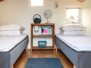 A room with two beds, a fan, a shelf with a basket and a painting, and a window. - Cozy Holiday Home in Funen near Sea (Frørup)