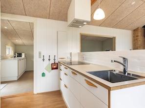 A modern kitchen with a central island, built-in appliances, and a hanging light fixture. - Cozy Holiday Home in Funen near Sea (Frørup)