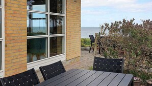A brick building with large windows, outdoor seating, and a view of the sea. - Cozy Holiday Home in Funen near Sea (Frørup)