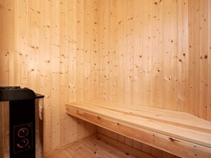 A sauna room with wooden walls and a bench.