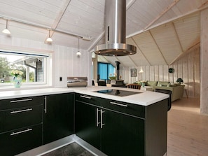A modern kitchen with a large island, dark cabinetry, and a stainless steel range hood.