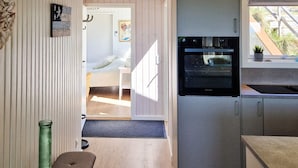 A compact kitchen with a built-in oven, a dining area with a bench, and a view of the outdoors. - 6 Person Holiday Home in Lokken (Lokken)
