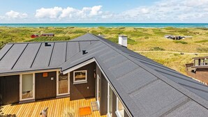 A coastal house with a wooden deck, a dark roof, and a view of the beach and dunes. - 6 Person Holiday Home in Lokken (Lokken)