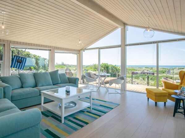 A spacious living area with a large window offering a view of the beach and dunes.