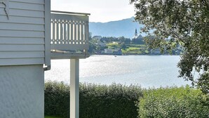 A view of a lake with a church and mountains in the background.