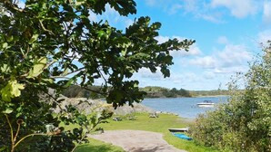 A pathway leading to a lakeside area with picnic tables and boats. - 6 Person Holiday Home in Lysekil (Lysekil)