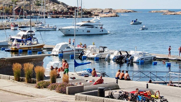 A marina with boats docked, people relaxing, and a rocky landscape in the background. - 6 Person Holiday Home in Lysekil (Lysekil)