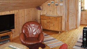 A wooden-paneled room with a leather armchair, a wooden cabinet, and a television on a wooden stand. - 6 Person Holiday Home in Brekstad (Orland)