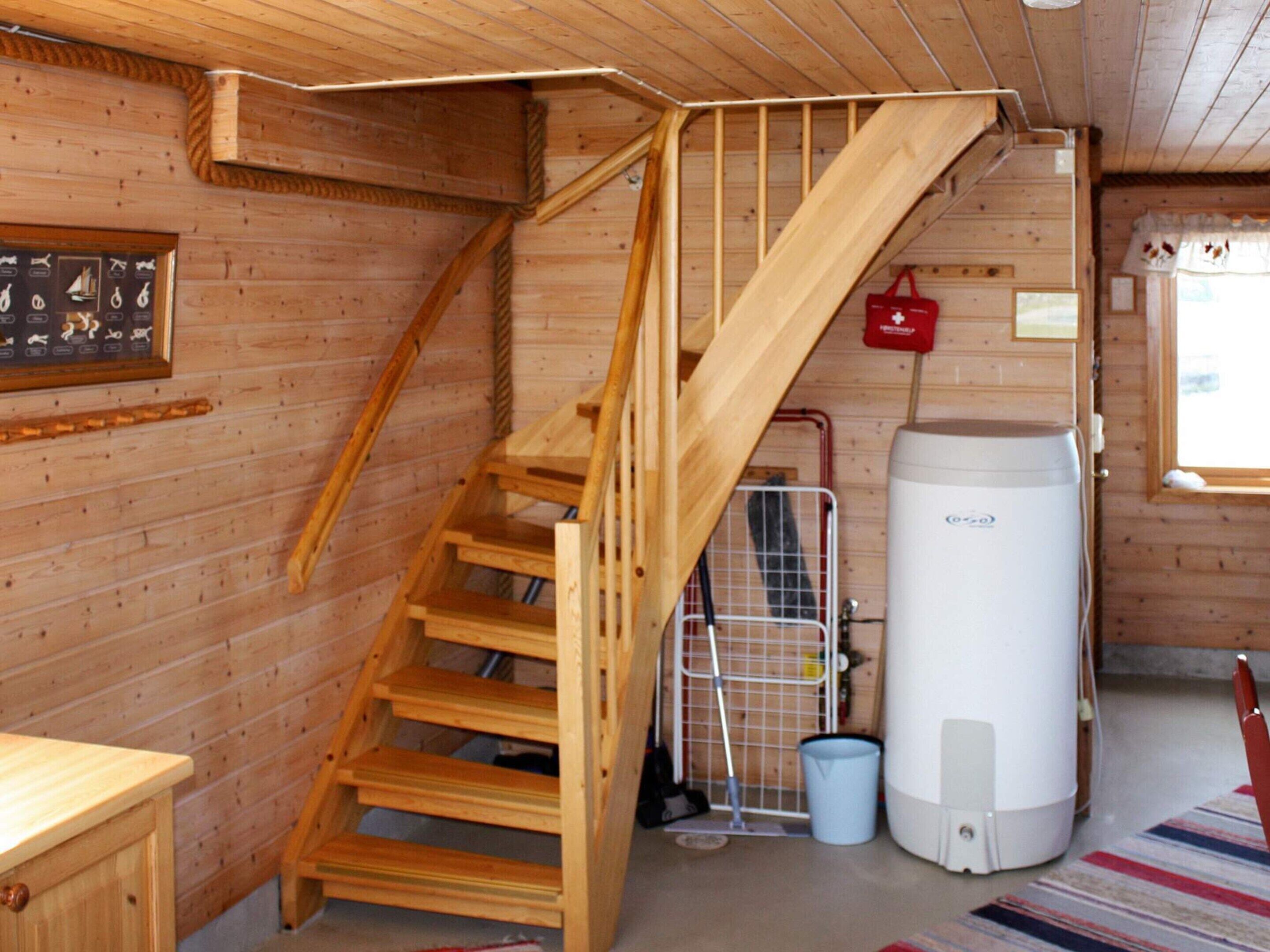A wooden staircase leading to an upper level, a water heater, and a framed picture on the wall.
