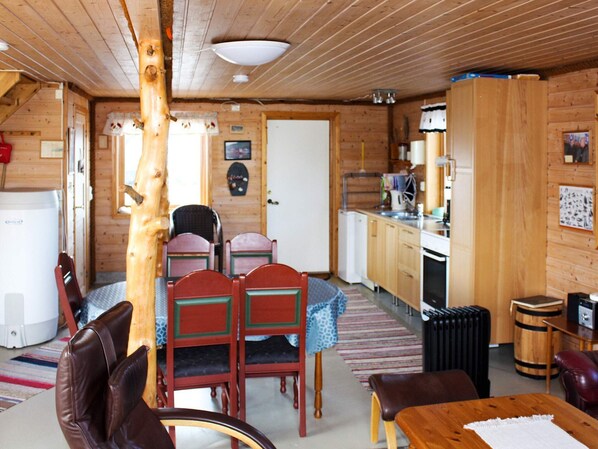A cozy cabin interior with a dining area, kitchen, and a large wooden tree trunk in the center. - 6 Person Holiday Home in Brekstad (Orland)