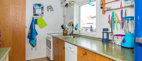 A kitchen with wooden cabinets, a dishwasher, a sink, and a window.