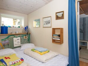 A bedroom with a bed, a shelf with books, a window, and a door. - 5 Person Holiday Home in Thyboron (Thyborøn)