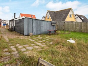 A residential area with a paved patio, a wooden table, and a fenced yard. - 5 Person Holiday Home in Thyboron (Thyborøn)