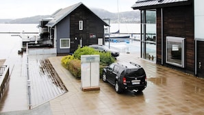 A modern hotel with a wooden exterior, a car parked in front, and a signboard. - 6 Person Holiday Home in Holmsbu (Asker)