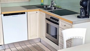 A compact kitchen with a dishwasher, stove, sink, and a coffee maker. - 6 Person Holiday Home in Holmsbu (Asker)