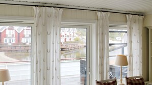 A room with a view of a waterfront, featuring a checkered chair and a lamp near the window. - 6 Person Holiday Home in Holmsbu (Asker)
