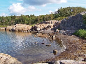 A rocky shoreline with clear water, surrounded by trees. - Holiday Home in Klövedal (Klovedal)