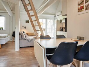 A modern, open-plan living space with a loft bedroom, a dining area, and a kitchen.