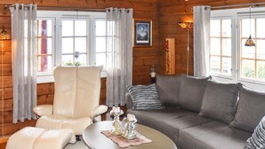 A cozy room with a leather chair, a grey sofa, a round coffee table, and a window with curtains.
