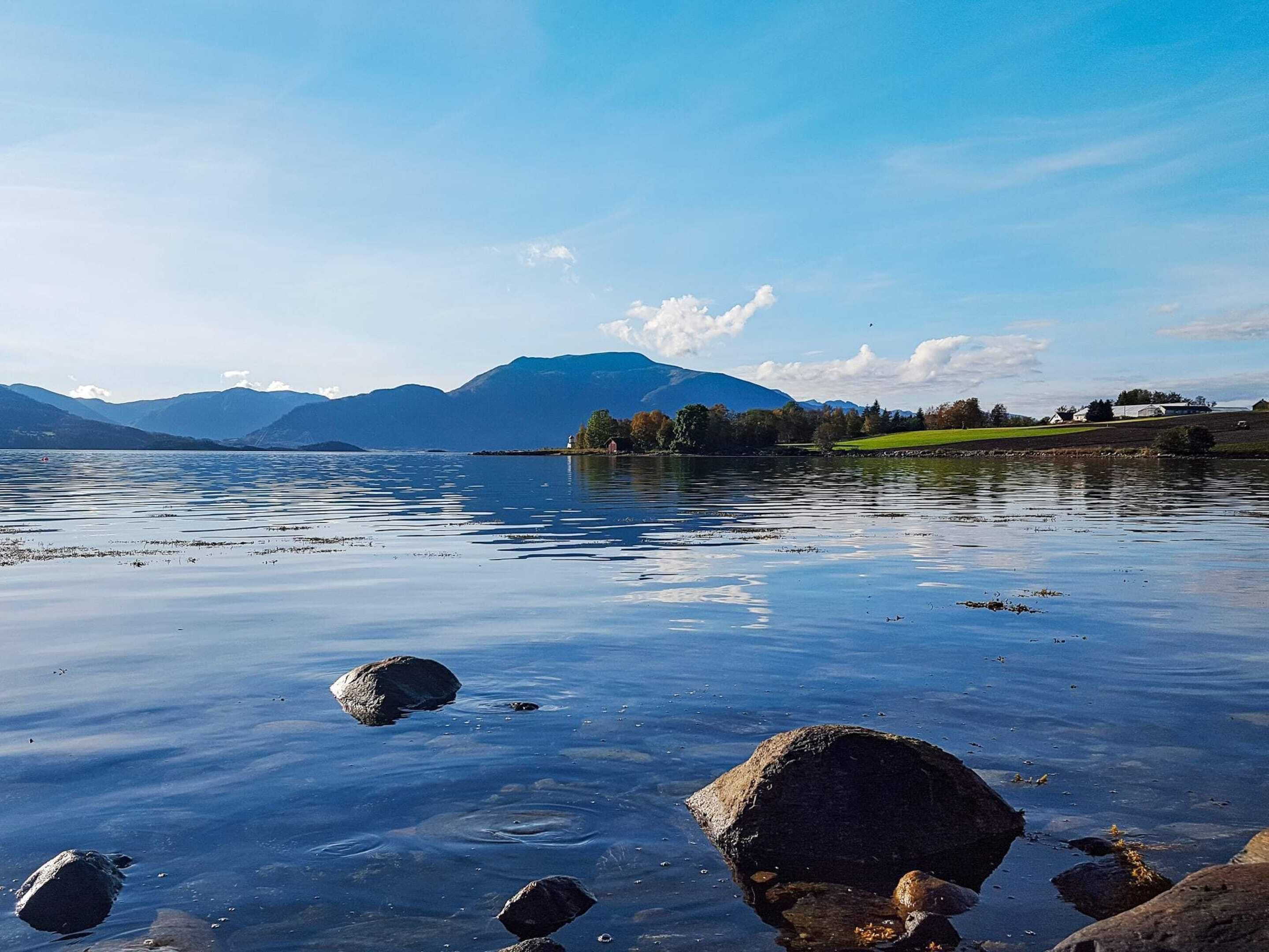 A calm lake with visible rocks and a distant mountain range.