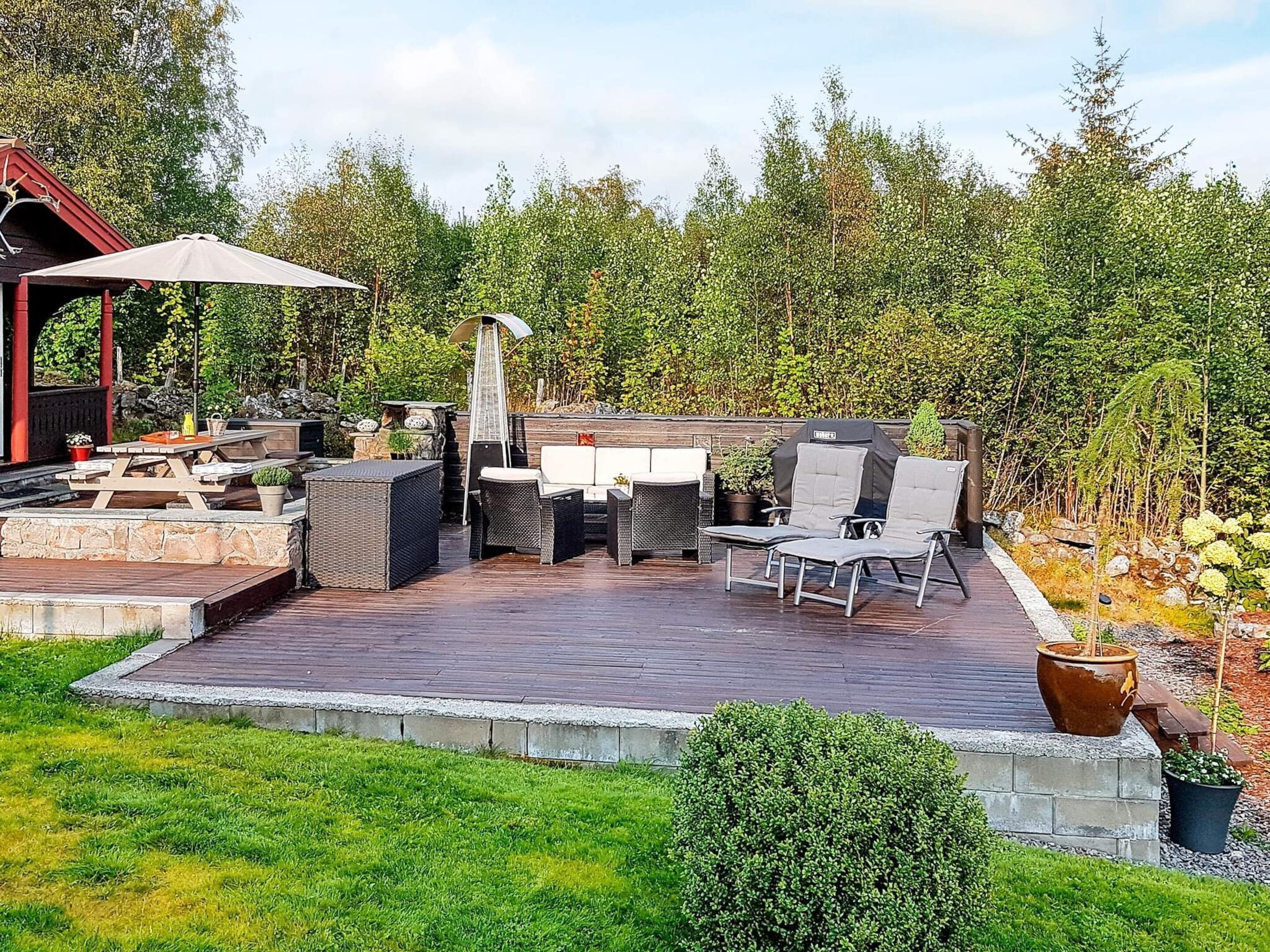 An outdoor patio with a stone deck, seating area, and a pergola.