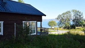 A wooden cabin with a blue-tiled roof overlooking a lake.