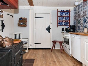 A kitchen with a wooden floor, white cabinetry, a stove, and a coffee maker. - 6 Person Holiday Home in Fano (Fano)