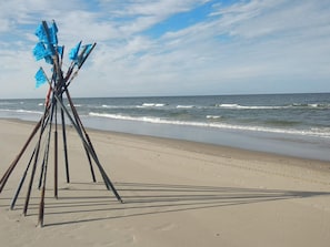 A beach with a structure made of sticks and blue fabric. - 6 Person Holiday Home in Fano (Fano)