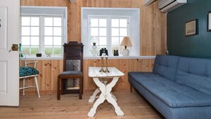 A room with wooden paneled walls, a blue sofa, a white table, and a chair. - 6 Person Holiday Home in Fano (Fano)