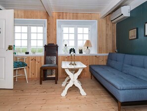 Une piÚce aux murs lambrés, avec un canapé bleu, une table blanche et une chaise.