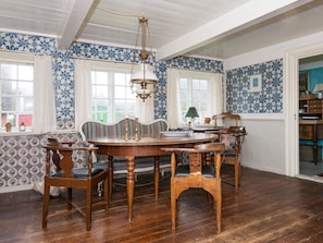 A dining room with a wooden table and chairs, a hanging light fixture, and patterned wallpaper. - 6 Person Holiday Home in Fano (Fano)