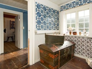 A room with blue and white patterned wallpaper, a window with curtains, and a wooden chest with red designs. - 6 Person Holiday Home in Fano (Fano)
