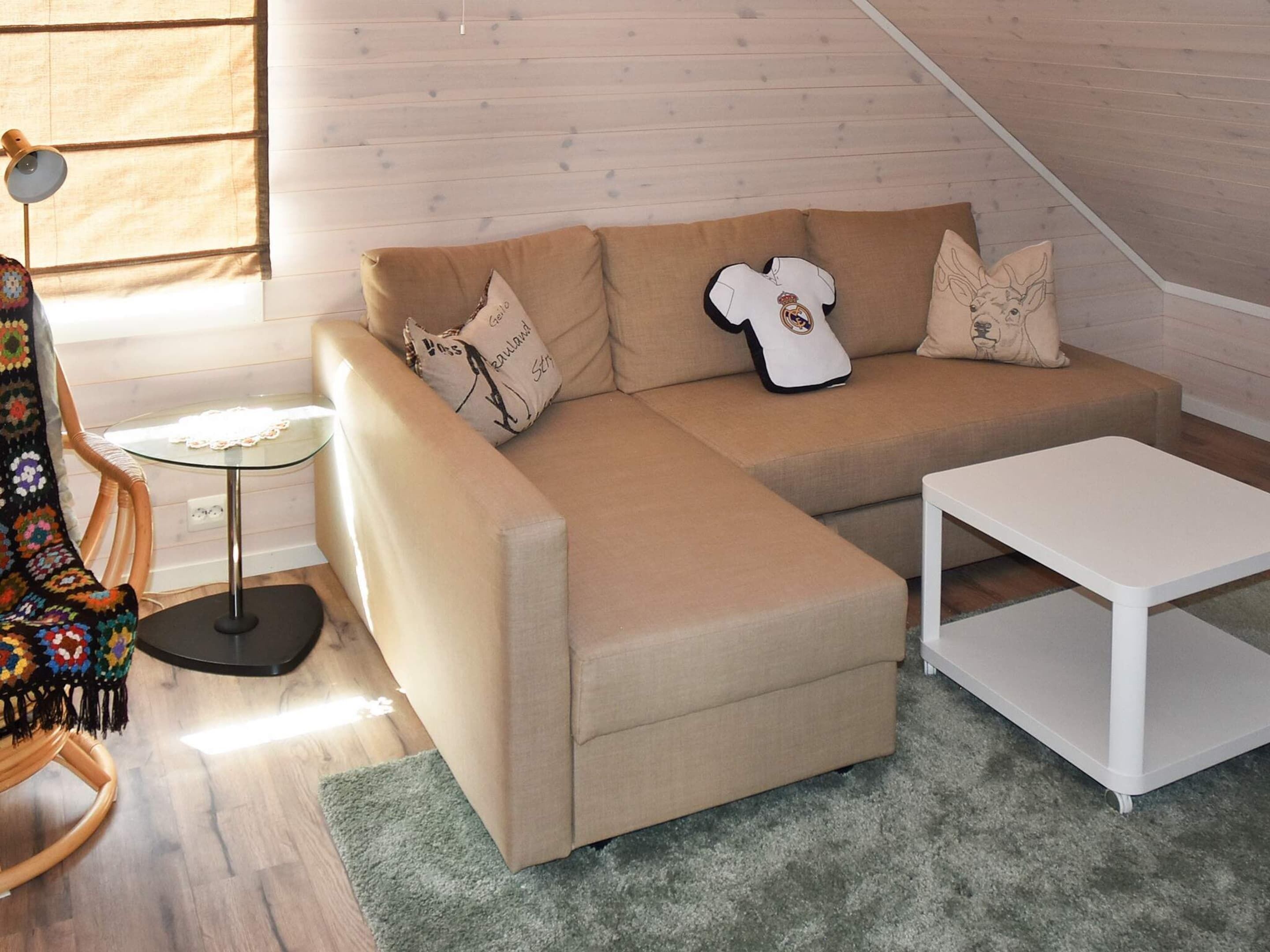 A cozy living room with a beige sectional sofa, a white coffee table, and a rocking chair.