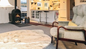 Ein gemütliches Wohnzimmer mit Kamin, einem bequemen Sessel und einem Marmortisch.