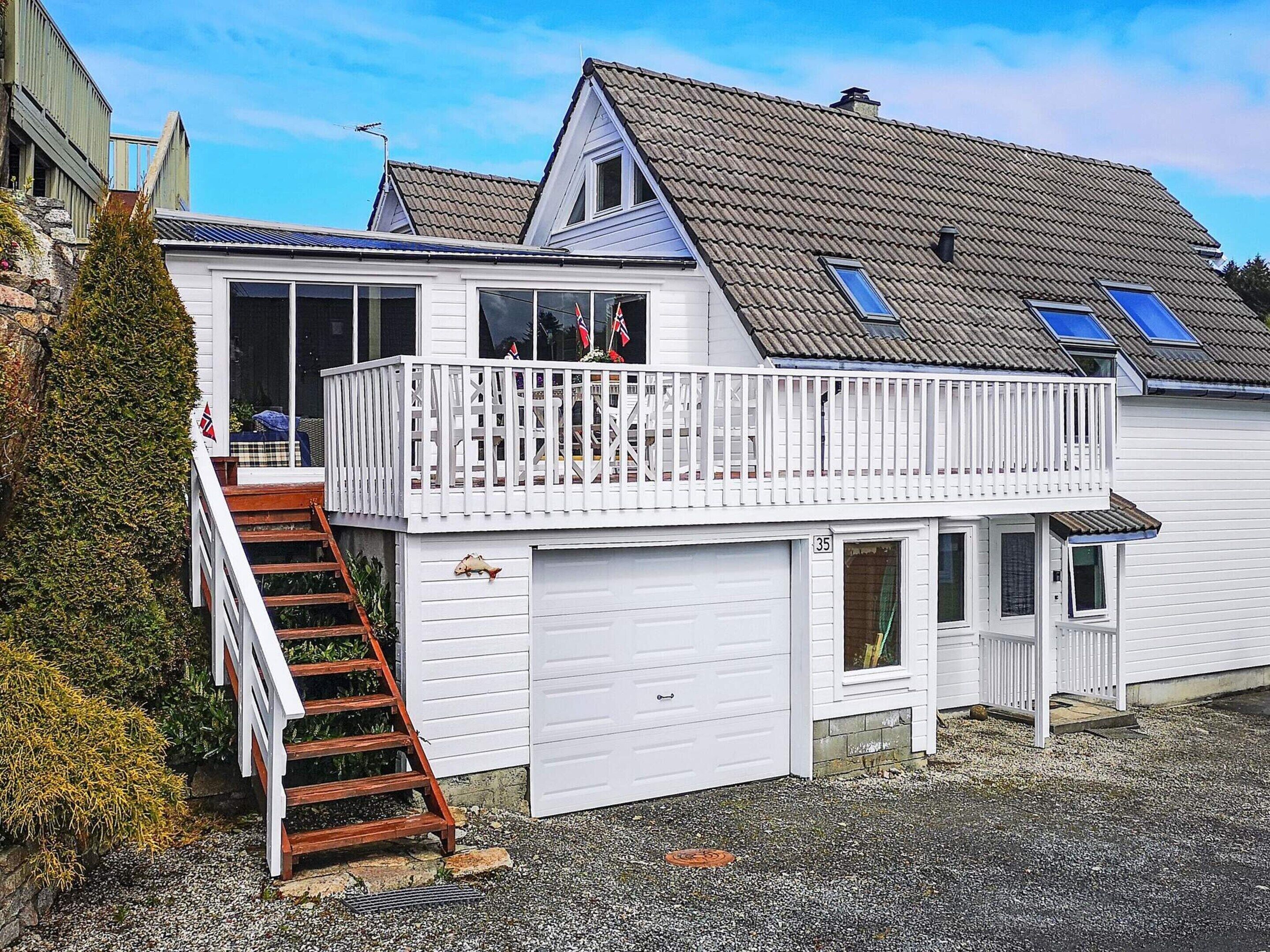 A two-story house with a balcony, a garage, and a staircase leading to the upper floor.