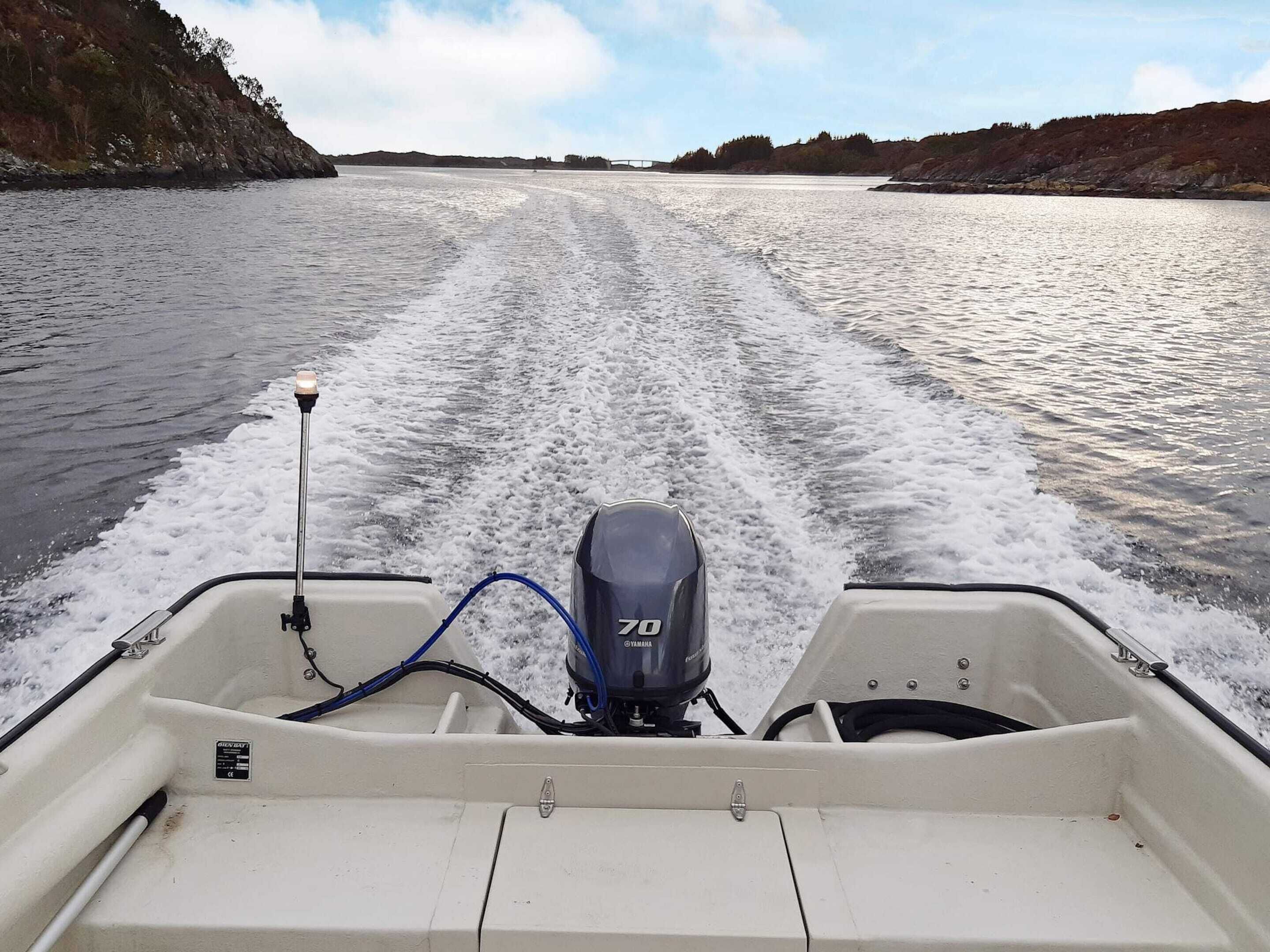 A boat with a Yamaha outboard motor, a wake, and a bridge in the distance.