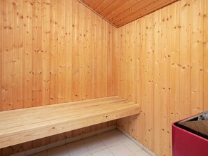 A wooden sauna with a bench and a red storage box.