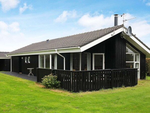 A black house with a sloped roof, large windows, and a fenced porch.