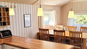 A compact kitchen with wooden cabinets, a built-in toaster, and a dining area with a wooden table and chairs. - 6 Person Holiday Home in Lokken (Lokken)