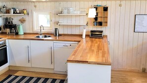 A kitchen with wooden countertops, a dishwasher, a coffee maker, and a hanging light fixture. - 6 Person Holiday Home in Lokken (Lokken)