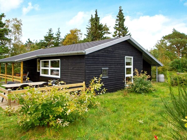 Cozy cabin nestled among lush greenery, featuring a sloped roof and a charming front porch.