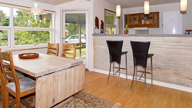 A modern kitchen with wooden cabinetry, a large island with stools, and a view of the outdoors. - 6 Person Holiday Home in Skjern (Skjern)