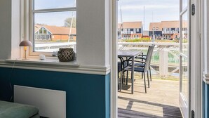 A room with a view of a dock and boats, a table with chairs, and a window with a lamp on the sill. - 4 Person Holiday Home in Borre (Borre)
