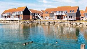 A waterfront property with multiple buildings, a dock, and a calm body of water. - 4 Person Holiday Home in Borre (Borre)