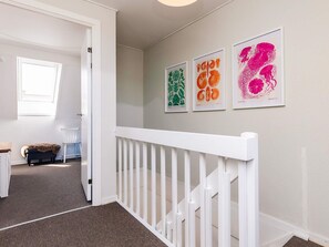 A hallway with a white railing, a door leading to another room, and three framed artworks on the wall. - 4 Person Holiday Home in Borre (Borre)