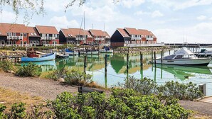 A marina with boats docked, a row of houses with red roofs, and a clear sky. - 4 Person Holiday Home in Borre (Borre)