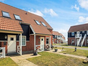 A row of townhouses with red-tiled roofs, white-framed windows, and a small front yard with a planter. - 4 Person Holiday Home in Borre (Borre)